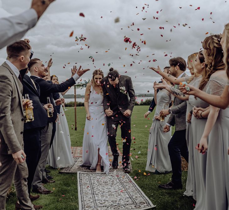 Bright Confetti Moment with Bride in Spaghetti Strap Wedding Dress and Groom in Wool Suit