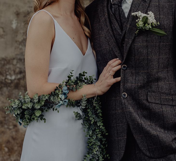 Boho Bride in Slip Wedding Dress and Ivy Garland with Groom in Three-piece Wool Suit Embracing