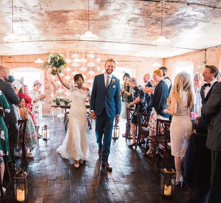 Bride in Lace Watters Dress with Bardot Neckline and Buttons Down Back | Blossom and Bluebird Cathedral Length Veil | Bridal Up Do | Groom in Royal Blue Three-Piece Suit from Moss Bros. with Silver Tie and Pocket Square from T.M.Lewin | Bridal Bouquet of Dusky Pink Roses, White Peonies, Sweetpeas, Coffee-Coloured Phlox and Foliage Tied with Cappuccino Silk Ribbon | Hurricane Lanterns | Wedding Ceremony at The West Mill | Smoke Bombs and Chinese Paper Fans Backdrop with Bride in Bardot Dress | Twig &amp; Vine Photography