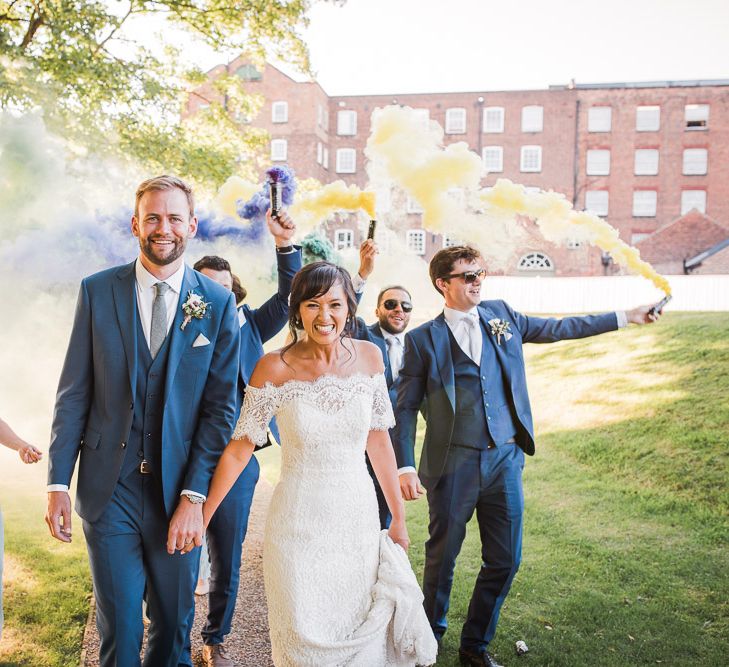 Wedding Party with Colourful Smoke Bombs | Bride in Lace Watters Dress with Bardot Neckline and Buttons Down Back | Bridal Up Do | Groom in Royal Blue Three-Piece Suit from Moss Bros. with Silver Tie and Pocket Square from T.M.Lewin | Bridesmaids in Sage Green Dresses with Embellished Straps from ASOS |  Smoke Bombs and Chinese Paper Fans Backdrop with Bride in Bardot Dress | Twig &amp; Vine Photography