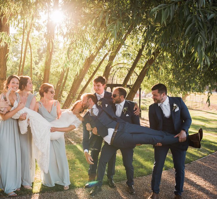 Bride in Lace Watters Dress with Bardot Neckline and Buttons Down Back | Bridal Up Do | Groom in Royal Blue Three-Piece Suit from Moss Bros. with Silver Tie and Pocket Square from T.M.Lewin | Bridesmaids in Sage Green Dresses with Embellished Straps from ASOS | Groomsmen in Royal Blue Moss Bros. Suits with Silver Ties and Pocket Squares from Tie Specialist UK | Smoke Bombs and Chinese Paper Fans Backdrop with Bride in Bardot Dress | Twig &amp; Vine Photography