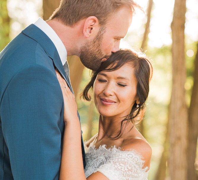 Bride in Lace Watters Dress with Bardot Neckline and Buttons Down Back | Bridal Up Do | Groom in Royal Blue Three-Piece Suit from Moss Bros. with Silver Tie and Pocket Square from T.M.Lewin | Smoke Bombs and Chinese Paper Fans Backdrop with Bride in Bardot Dress | Twig &amp; Vine Photography