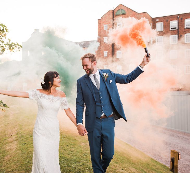 Bride and Groom with Colourful Smoke Bombs | Bride in Lace Watters Dress with Bardot Neckline and Buttons Down Back | Bridal Up Do | Groom in Royal Blue Three-Piece Suit from Moss Bros. with Silver Tie and Pocket Square from T.M.Lewin | Smoke Bombs and Chinese Paper Fans Backdrop with Bride in Bardot Dress | Twig &amp; Vine Photography