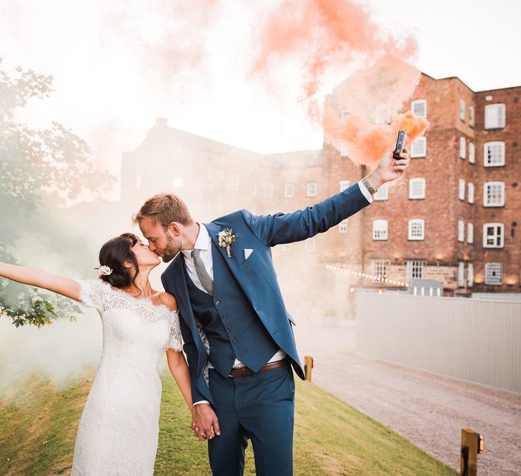 Bride and Groom with Colourful Smoke Bombs | Bride in Lace Watters Dress with Bardot Neckline and Buttons Down Back | Bridal Up Do | Groom in Royal Blue Three-Piece Suit from Moss Bros. with Silver Tie and Pocket Square from T.M.Lewin | Smoke Bombs and Chinese Paper Fans Backdrop with Bride in Bardot Dress | Twig &amp; Vine Photography