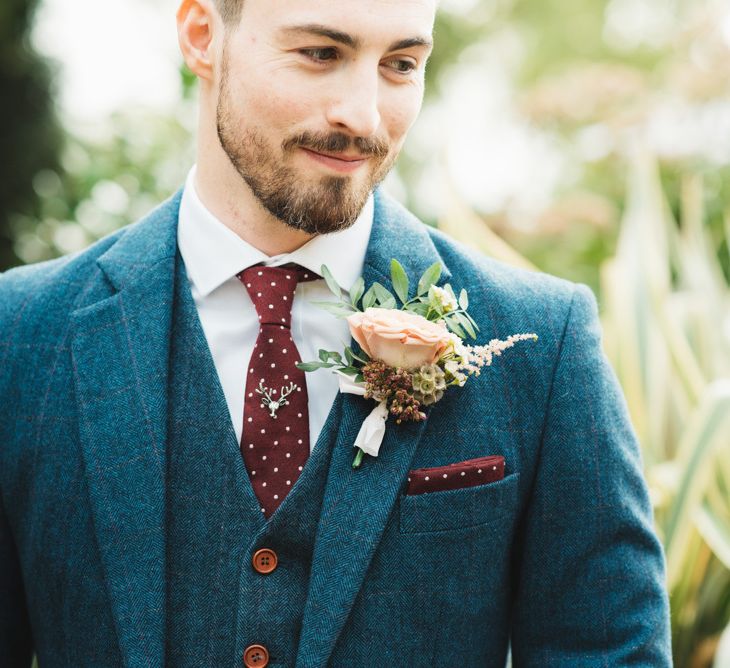 Groom Navy Tweed Suit with Burgundy Tie and Floral Button Hole