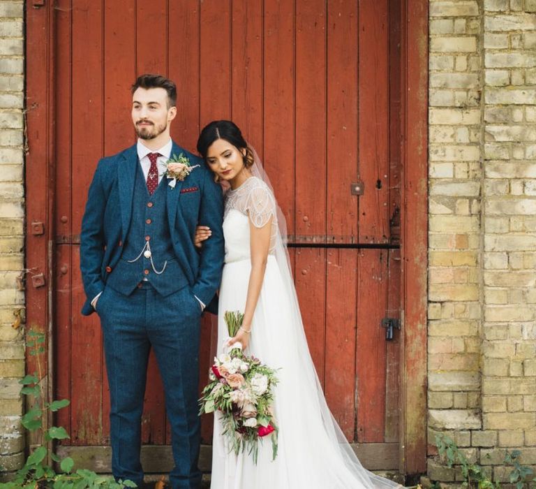 Groom Wearing Tweed Navy Suit with Bride Holding Autumnal Bouquet