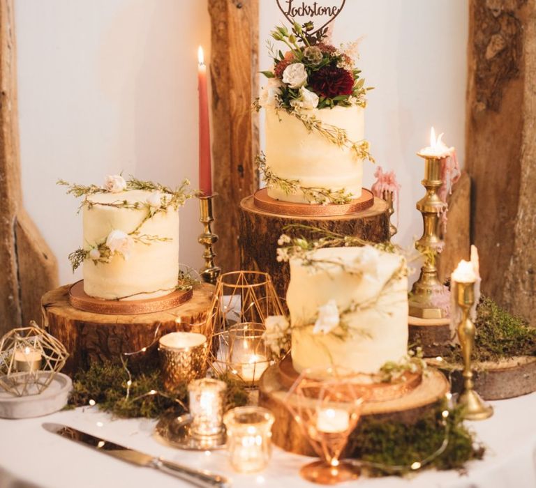 Beautiful Rustic Cake Table with Candles and Foliage with Cakes on Tree Slices