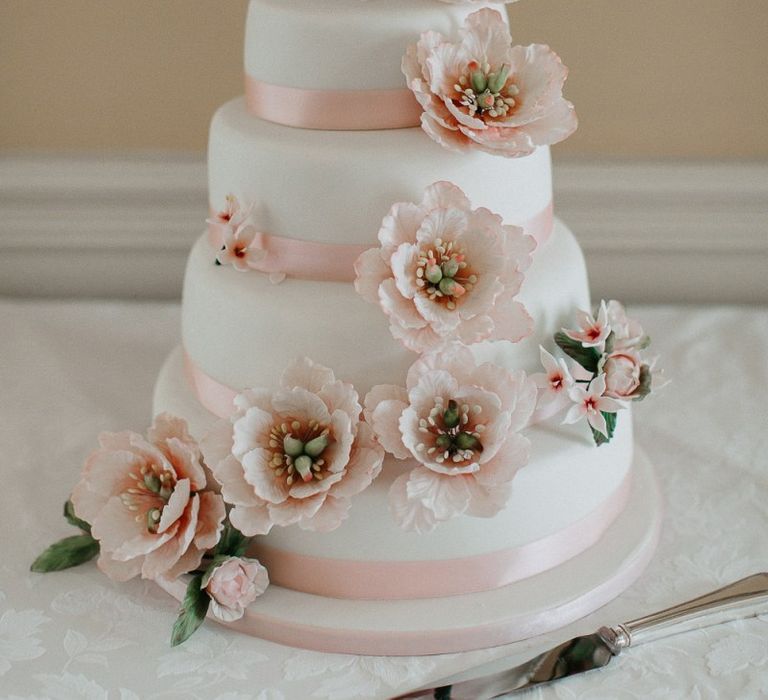 White Wedding Cake with Floral Decor and Cute Cake Toppers