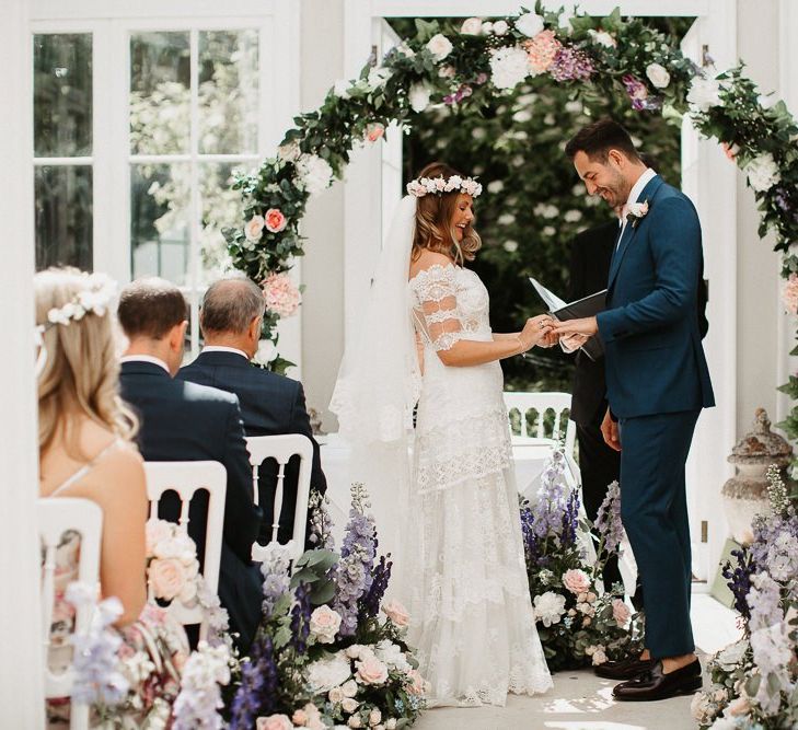 Bride and Groom Exchanging Vows Under Homemade Flower Arch