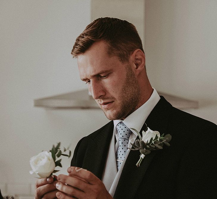 Groom Putting on His White Rose Buttonhole