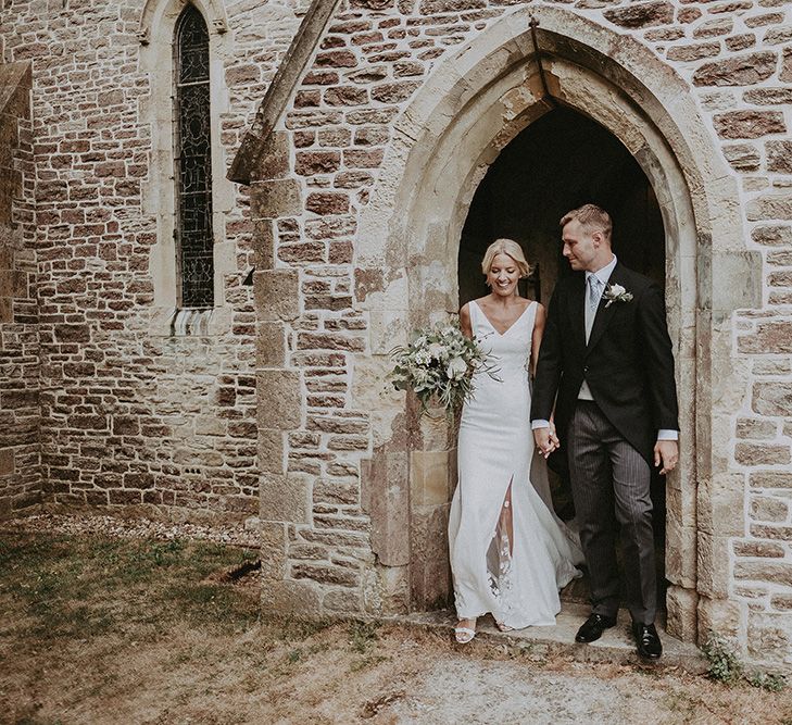 Bride in Rime Arodaky Wedding Dress and Groom in Traditional Morning Suit Exiting the Church