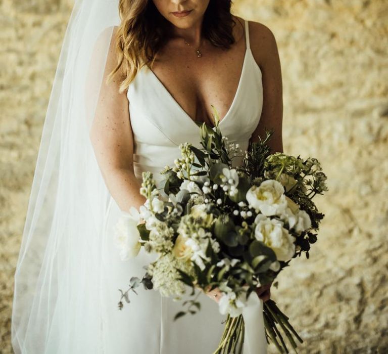 Bride in minimalist Sassi Holford wedding dress with bouquet