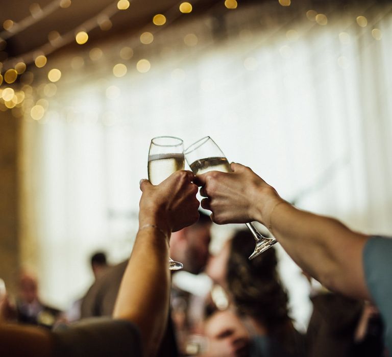 Guests toast the bride and groom under fairy light canopy