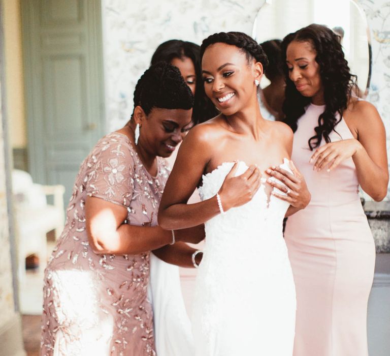 Mother of the bride helping her daughter into her wedding dress