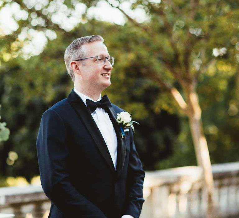 Groom standing at the altar in a tuxedo for destination wedding with pink bridesmaid dresses