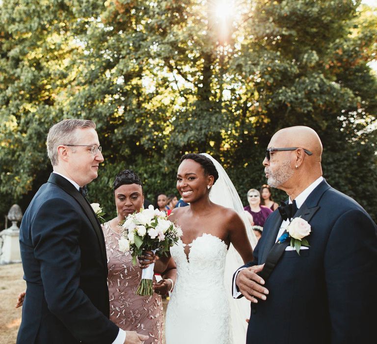 Mother and Father of the bride giving their daughters hand to the groom