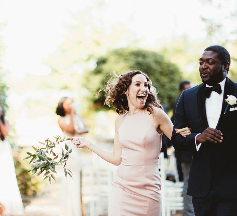 Groomsmen and bridesmaids in pink dresses walking up the aisle