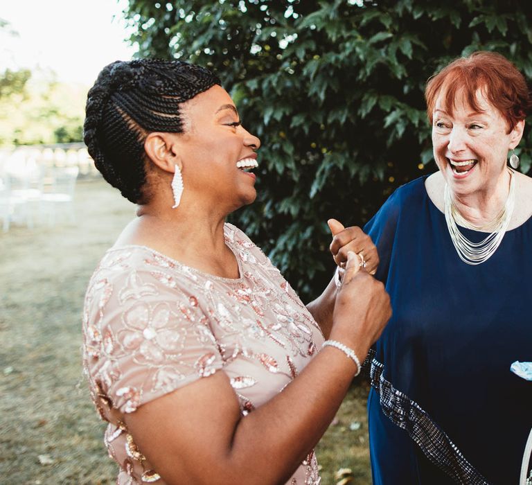 Mother of the bride in pink embellished wedding dress talking to guests