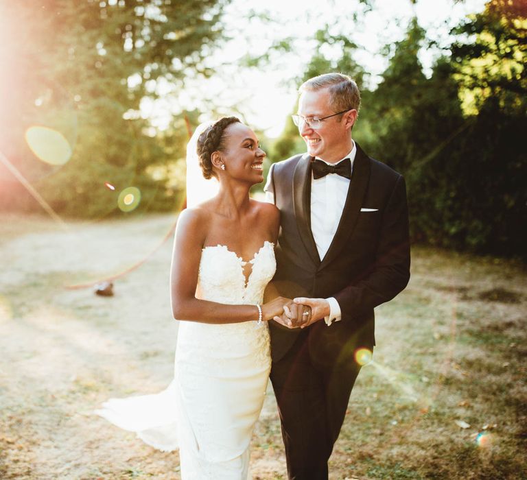 Bride and groom laughing at holding hands during golden hour