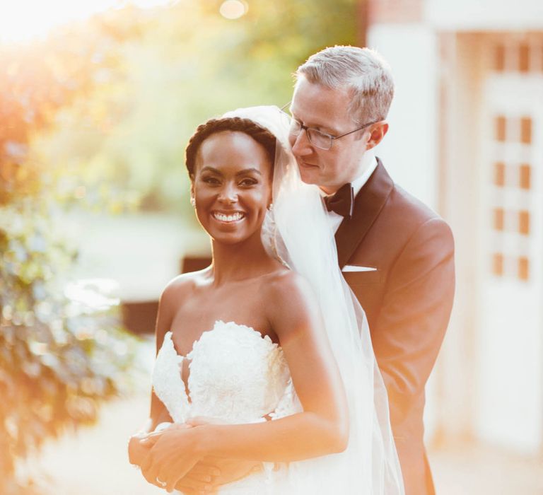 Groom in tuxedo embracing his bride in a strapless wedding dress