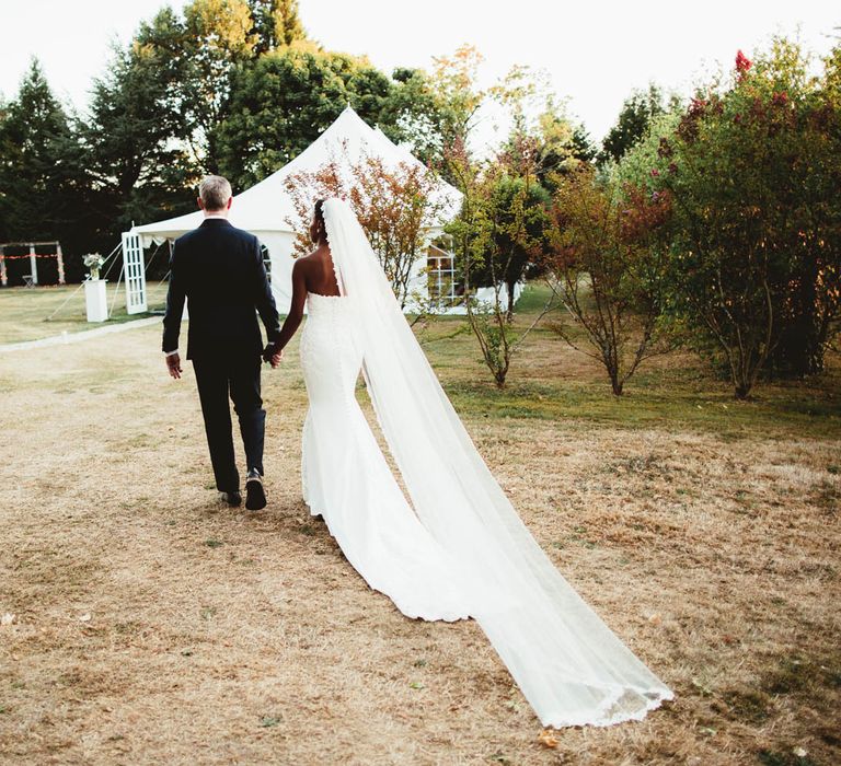 Bride and groom walking towards their marquee reception at Chateau La Durantie, France