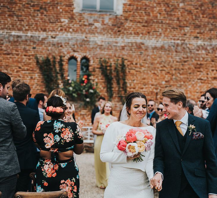 Bride in Halfpenny London Separates of Laura Top with Cowl Back and Long Sleeves, Silk Cami and Laser Cut Palm Skirt | Groom in Navy Tweed Suit by Walker Slater with Yellow Tie and Patterned Pocket Square | Colourful Bridal Bouquet of Pink and White Peonies | Outdoor Wedding Ceremony at Abbey Hall Creative Space | 'Frida Kahlo' Flower Crown, Halfpenny London Bridal Separates and Colourful Bouquets with Peonies for Suffolk Wedding | From The Smiths Photography