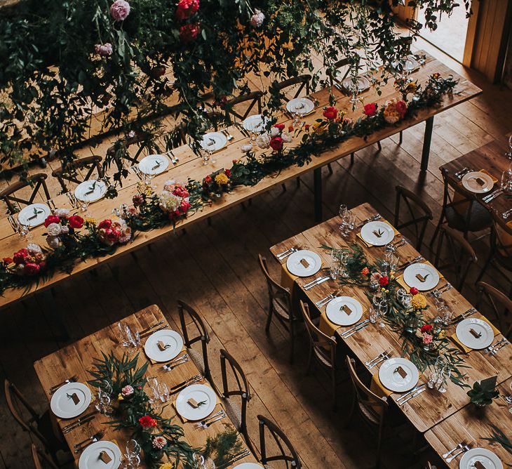 Long Wooden Banquet Tables | Yellow Napkins | Pink, Orange and Yellow Table Flowers with Foliage | Kraft Label Place Settings | Wedding Reception at Abbey Hall Creative Space | 'Frida Kahlo' Flower Crown, Halfpenny London Bridal Separates and Colourful Bouquets with Peonies for Suffolk Wedding | From The Smiths Photography