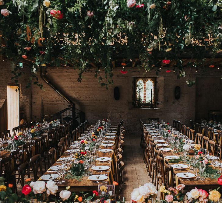 Long Wooden Banquet Tables | Yellow Napkins | Pink, Orange and Yellow Table Flowers with Foliage | Kraft Label Place Settings | Wedding Reception at Abbey Hall Creative Space | 'Frida Kahlo' Flower Crown, Halfpenny London Bridal Separates and Colourful Bouquets with Peonies for Suffolk Wedding | From The Smiths Photography