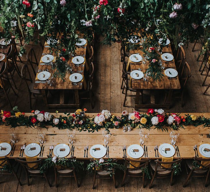 Long Wooden Banquet Tables | Yellow Napkins | Pink, Orange and Yellow Table Flowers with Foliage | Kraft Label Place Settings | Wedding Reception at Abbey Hall Creative Space | 'Frida Kahlo' Flower Crown, Halfpenny London Bridal Separates and Colourful Bouquets with Peonies for Suffolk Wedding | From The Smiths Photography