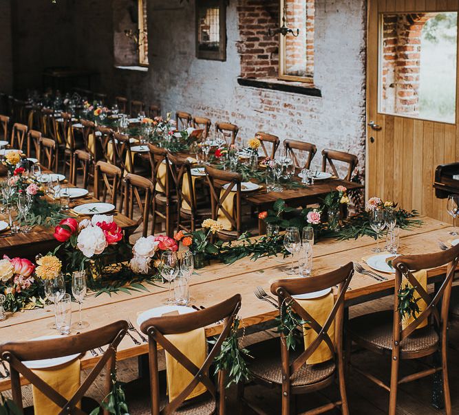 Long Wooden Banquet Tables | Yellow Napkins | Pink, Orange and Yellow Table Flowers with Foliage | Kraft Label Place Settings | Wedding Reception at Abbey Hall Creative Space | 'Frida Kahlo' Flower Crown, Halfpenny London Bridal Separates and Colourful Bouquets with Peonies for Suffolk Wedding | From The Smiths Photography