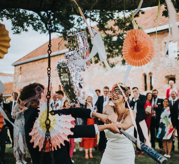 Bride in Halfpenny London Separates of Laura Top with Cowl Back and Long Sleeves, Silk Cami and Laser Cut Palm Skirt | Flower Crown with Pink Peony | Groom in Navy Tweed Suit by Walker Slater with Yellow Tie and Patterned Pocket Square | Piñata | 'Frida Kahlo' Flower Crown, Halfpenny London Bridal Separates and Colourful Bouquets with Peonies for Suffolk Wedding | From The Smiths Photography