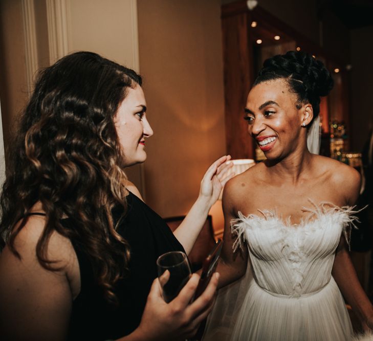 Groom in strapless Mira Zwillinger wedding dress talking to a guest