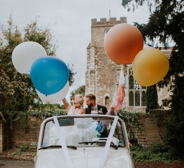 Bride and Groom in Convertible VW Beatle Holding Giant Bright Balloons