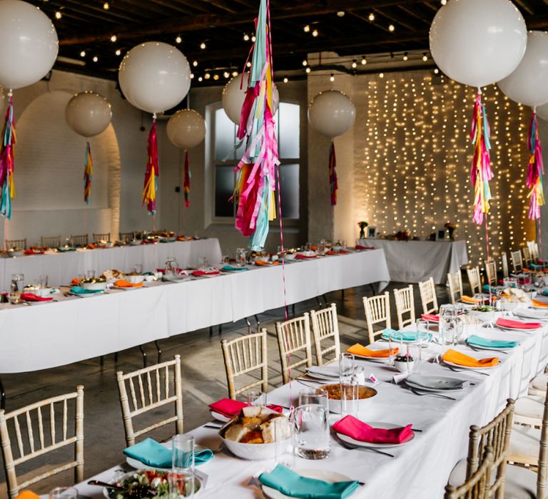 Industrial Wedding Venue Decorated with Fairy Light and Giant Balloons with Colourful Tissue Tassels