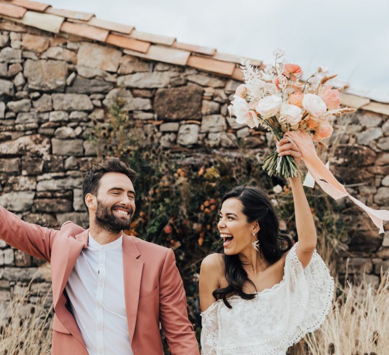 Stylish Bride in Grace Loves Lace Wedding Dress and Groom in Dusky Pink Suit Celebrating