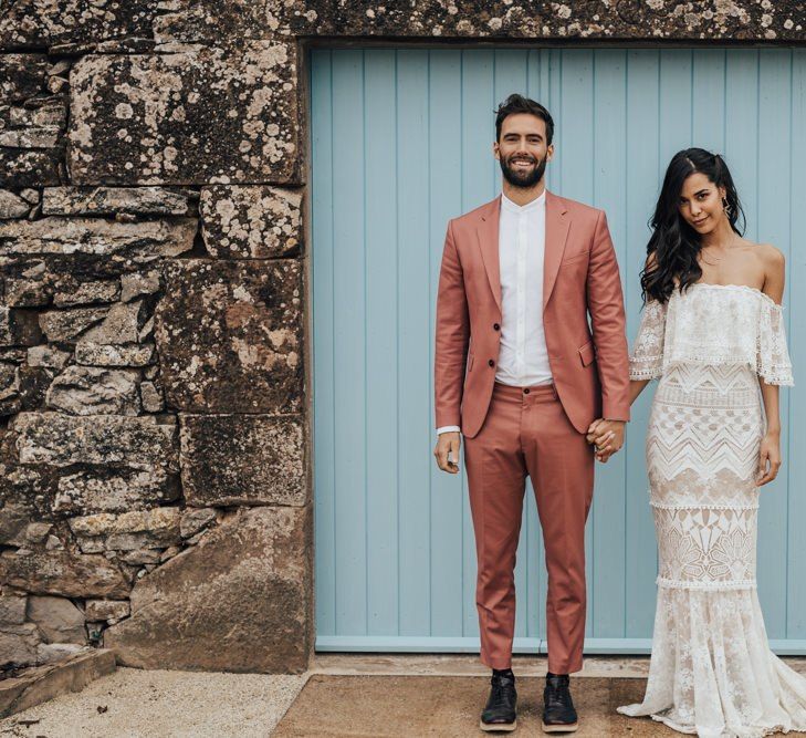 Bride in Bardot Grace Love Laces Wedding Dress and Groom in Coral Wedding Suit Holding Hands