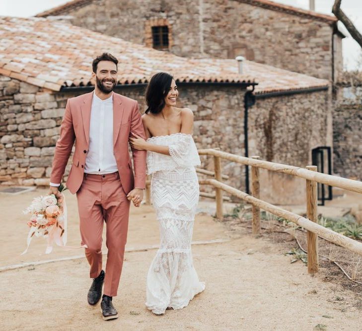 Bride in Bardot Grace Loves Lace Wedding Dress and Groom in Coral Suit Walking Arm in Arm at Barcelona Venue This Must Be the Place