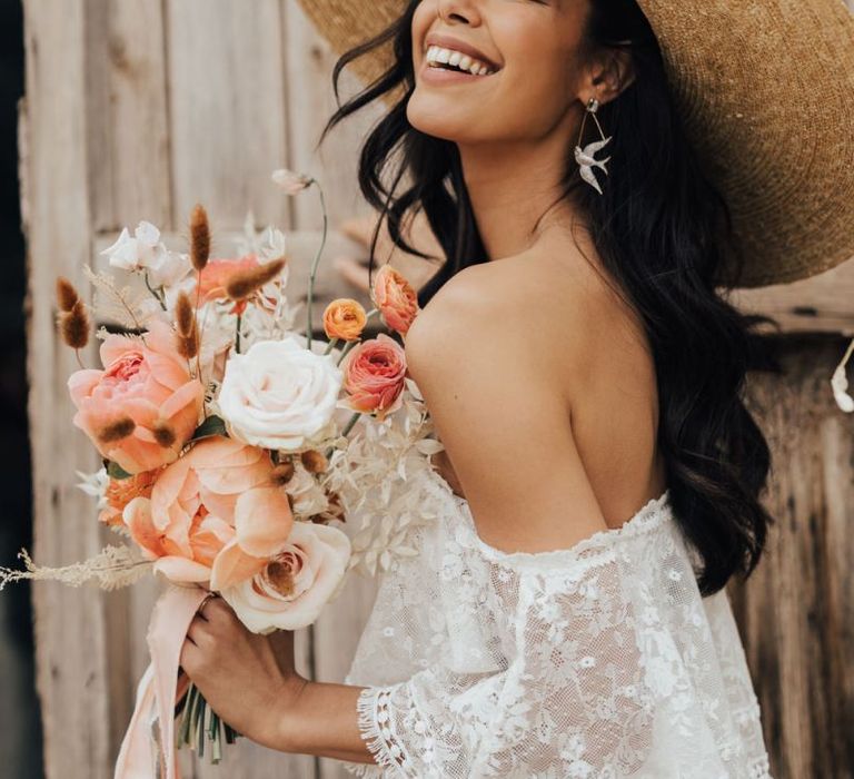 Beautiful Bride in Straw Hat Holding a White and Coral Wedding Bouquet