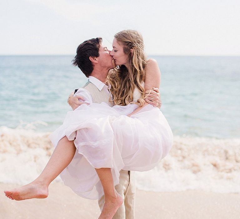 Groom lifting his bride in the surf