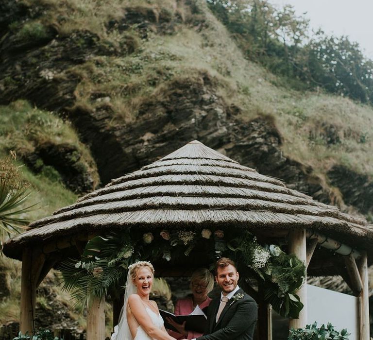 Coastal wedding ceremony at Tunnels Beaches in Devon with bride in lace in Willowby by Watters wedding dress and groom in chino's and blazer