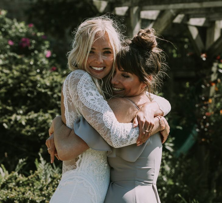 Bride in Grace Loves Lace Inca Gown with Boat Neck, Lace Sleeves and Low Back | Bridesmaid in Grey Cold Shoulder Dress by Rewritten | Mykonos Rewritten Bridesmaid Dresses for an Epic Clifftop Coastal Wedding | Nic Ford Photography