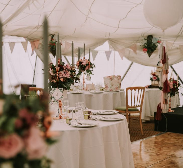 Marquee with Draped Ceiling at The Druidstone | Pastel Bunting | Grey Tapered Candles | Rose Gold Candelabras | Giant White Balloons with Grey, Blush and Burgundy Tassels | Table Centrepieces of Blush and Burgundy Flowers with Foliage | Mykonos Rewritten Bridesmaid Dresses for an Epic Clifftop Coastal Wedding | Nic Ford Photography