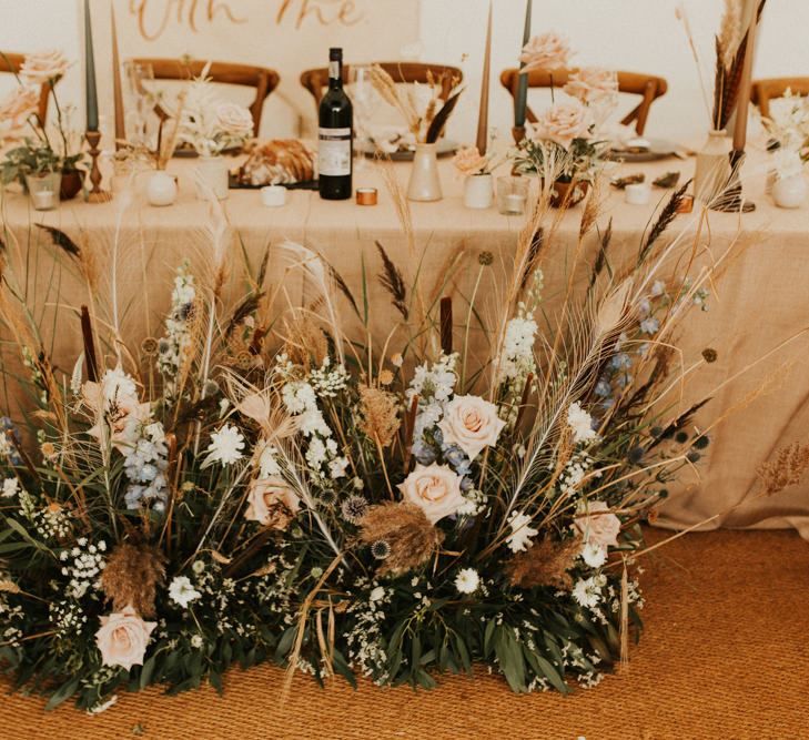 Pink and blue flowers with dried grasses and foliage for August 2020 wedding reception