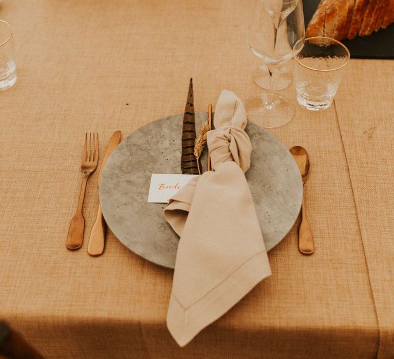 Boho place setting with concrete plate, gold cutlery and linen napkin