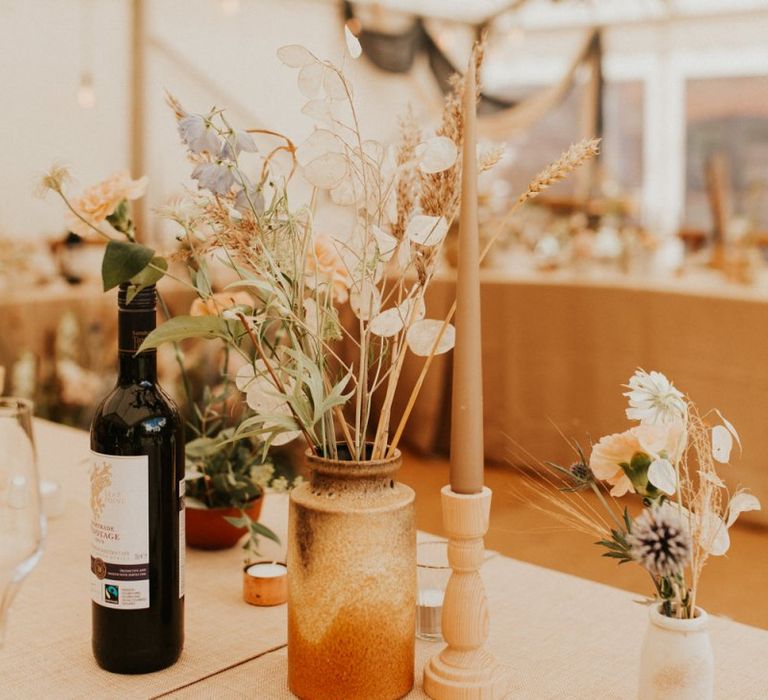 Flower stems and dried grasses in ink wells for bohemian August 2020 wedding reception