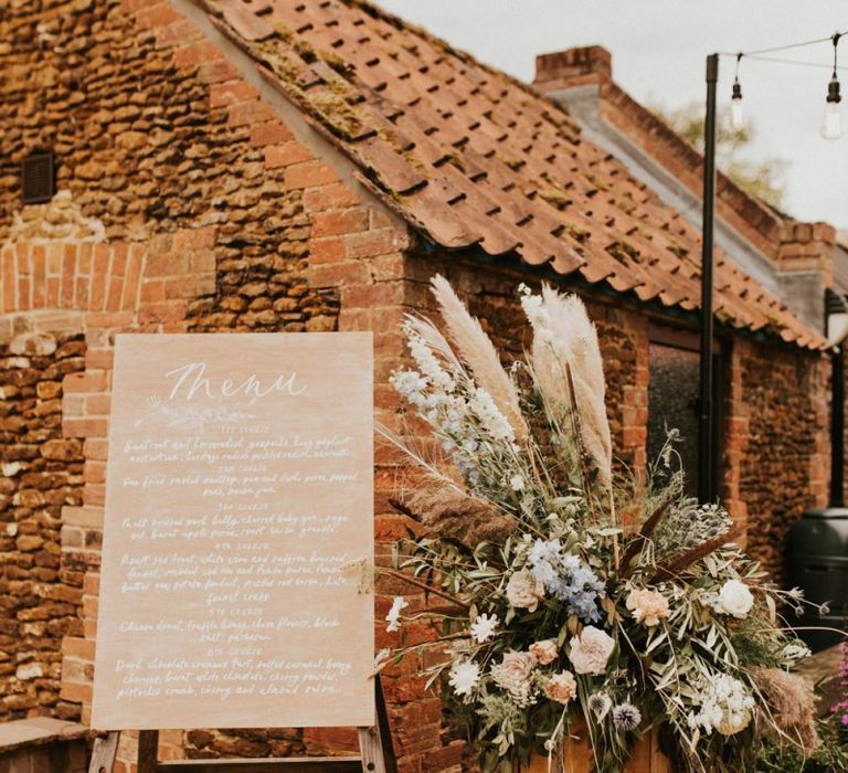 Wooden menu sign and floral arrangement at August 2002 wedding