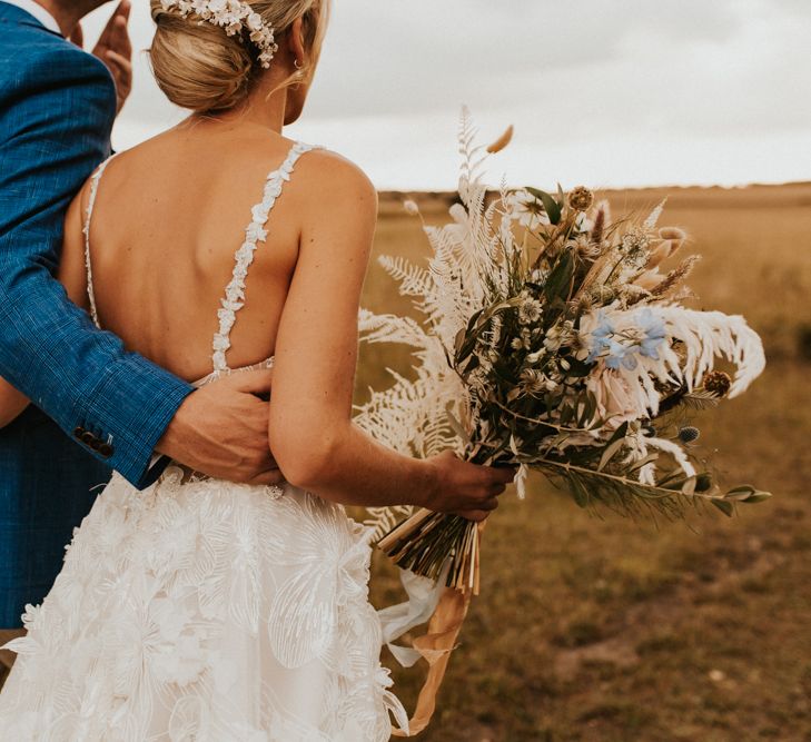 Groom in blue blazer embracing his bride in a Galia Lahav wedding