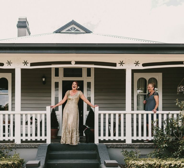 Bride Standing on a Porch in Her Sequin Gold Wedding Dress