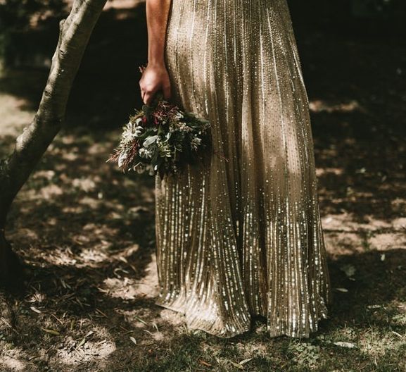 Bride Holding Her Protea Wedding Bouquet Next to Her Sequin Gold Wedding Dress