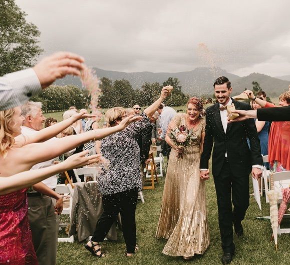 Confetti Moment  with Bride in Sequin Gold Wedding Dress and Groom  in Dark Suit and Wood Bow Tie